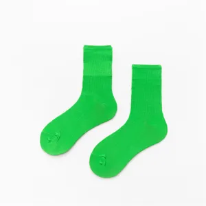 Gros plan de chaussettes en coton vert vif avec manchette côtelée fine et texture unie.
