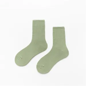 Gros plan détaillé de chaussettes montantes en coton vert clair avec texture tricotée.