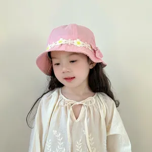 Close-up of cute pink kids bucket hat with white daisy lace trim and side bow detail.