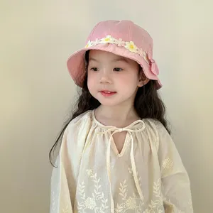 Detailed close-up shot of the cute pink baby bucket hat with delicate floral lace trim and soft fabric.