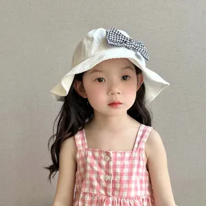 Cute white cotton bucket hat with houndstooth bow detail, close-up view for kids