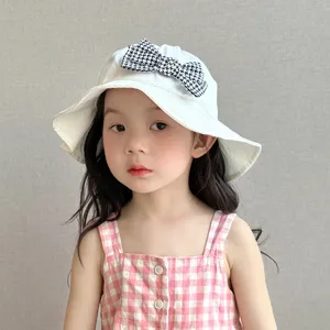 Detail shot of cute kids bucket hat featuring a stylish houndstooth bow and soft white fabric.