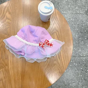 Kids purple bucket hat with white mesh ruffles, pearl trim, and plaid bow detail.