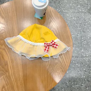 Detailed view of cute yellow baby bucket hat with white mesh lace and plaid bow decor.