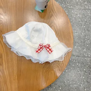 White baby sun hat with mesh ruffle, pearl trim and red plaid bow for cute toddlers.