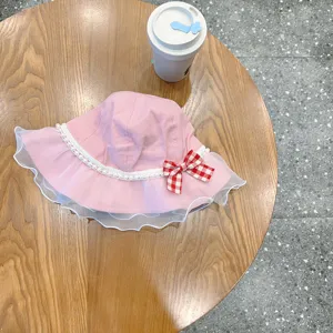 Cute pink baby bucket hat detail, featuring delicate white lace trim and lovely red checkered bow.