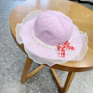 Cute pink baby bucket hat with white pearl lace ruffle and red plaid bow for summer.