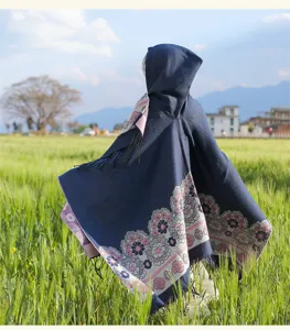 Detailed view of the ethnic floral hooded cape shawl showcased in a natural green field setting.