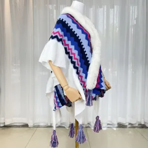 Detailed view of women knitted winter cape with faux fur collar, colorful zigzags and fringes.