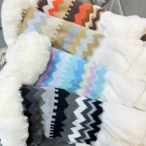 Detailed view of colorful zigzag knit shawl with plush white fur collar texture.