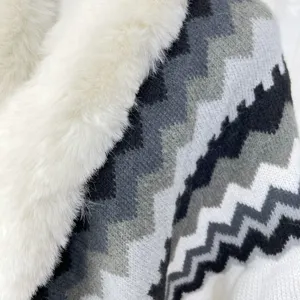 Close-up of knit cape detail showcasing black and white wave pattern and soft faux fur collar.