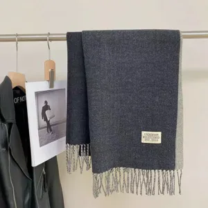 Detail view of a cozy dark grey reversible cashmere feel scarf with fringe hem texture.