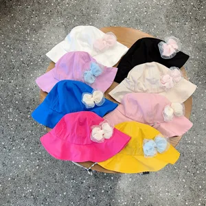 Detailed view showing multiple colorful children bucket hats with mesh bows arranged on wooden table.