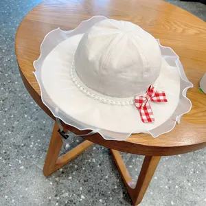 Cute baby sun bucket hat with lace ruffle, pearl trim and red bow for spring and summer.