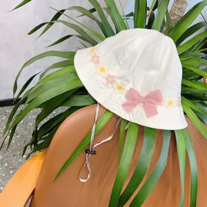 Children white bucket hat detail shot, cute embroidered floral trim and pink bow, adjustable strap.