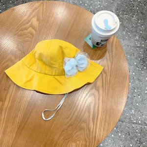 Detail shot of yellow baby bucket hat with light blue mesh bow and adjustable strap.