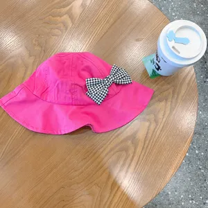 Cute pink kids bucket hat with black and white houndstooth bow, perfect for spring.