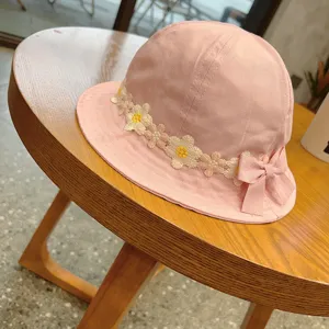 Cute pink baby bucket hat with daisy embroidery and bow detail on wooden table detail view