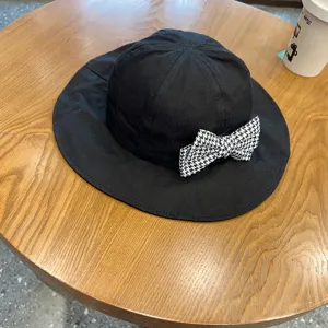 Close-up detail of children's black bucket hat featuring a chic houndstooth bow decoration.