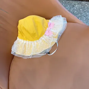 Close-up of cute yellow kids bucket hat with white polka dot lace brim and pink bow detail.