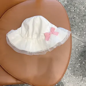 Detailed view of white baby bucket hat with cute pink bow and delicate lace mesh brim.