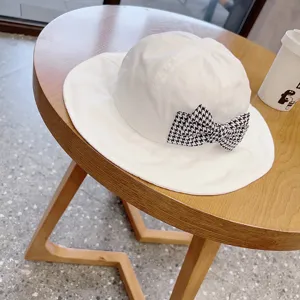 Detailed view of cute baby white bucket hat with houndstooth bow for toddler girls spring.
