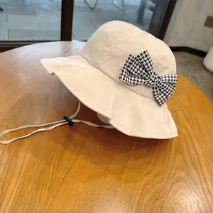 Cute beige kids bucket hat with black and white houndstooth bow and adjustable chin strap sun hat