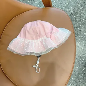 Close-up of pink baby bucket hat with white dotted lace trim, cute bow and adjustable chin strap.
