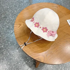Detailed view of white baby bucket hat featuring floral crochet and cute pink bow decor.