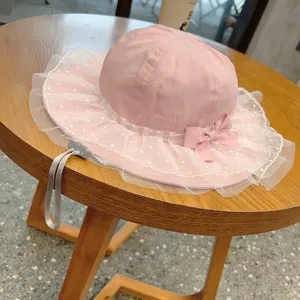 Cute infant pink bucket hat with lace mesh bow and adjustable strap for baby girls spring sun.