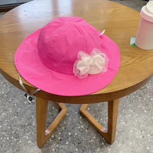 Cute pink baby bucket hat with white lace bow, adjustable summer sun protection hat for kids.