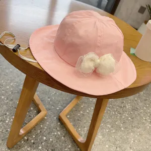 Detailed view of cute pink baby sun hat with white lace bow and adjustable strap