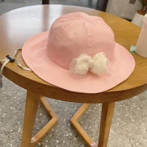 Cute pink baby fisherman hat detail featuring a sweet white lace bow and adjustable chin strap.