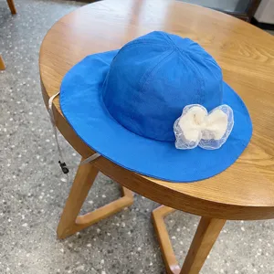 Detailed view of the bright blue children sun hat with white mesh lace bow and adjustable chin strap.