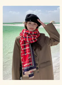 Detailed view of the stylish red plaid scarf and chic black beret outfit in a scenic outdoor setting.