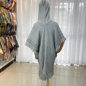 Grey hooded knitted cape detail showing back woven texture, tassel hem and mannequin display.