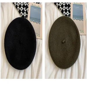 Detailed view of women wool beret in black and green, classic autumn winter painter hat.