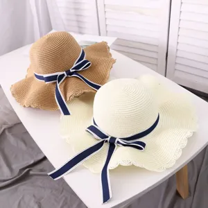 Wide brim straw sun hat with navy bow ribbon, perfect for summer beach vacation and outdoor travel.