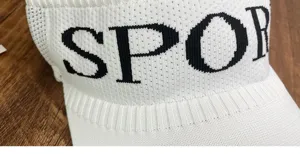 Close-up detail of white knitted empty-top sports sun visor hat, showing knitted letter texture.