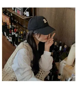 Primer plano detalle de la bonita gorra de beisbol negra con bordado logo R en el bar.