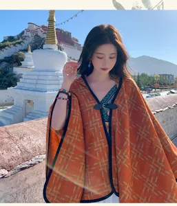 Detailed view of the warm orange cape outdoors, highlighting the geometric pattern and soft texture.