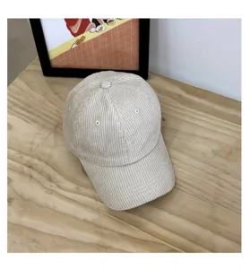 Detailed close-up shot of a beige corduroy baseball cap placed on wooden table, casual.