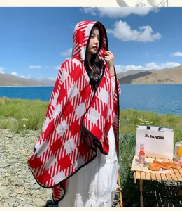 Outdoor scenic detail view of a warm red and white houndstooth hooded cape for travel style.
