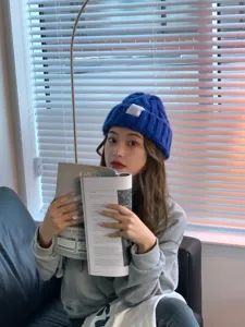 Detailed shot of a stylish blue knit beanie hat worn in a cozy indoor daily scene.