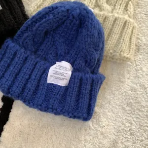 Thick knit beanie winter wool hat detail showing cozy ribbed texture and fabric label design.