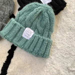 Chunky knit beanie detail showing soft mint green wool texture and stitched label design.