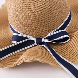Close-up detail of a summer straw sun hat featuring an elegant navy blue bow ribbon.