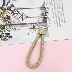 Beige braided leather keychain lanyard with metal ring and lobster clasp close-up view.