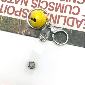 Close-up detail of metal keychain clasp, spring dog clip and yellow bell accessory part.