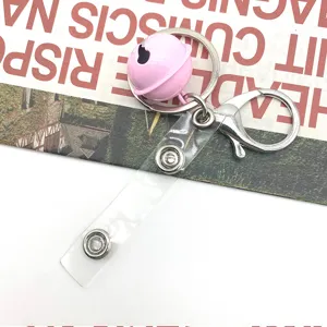 Close-up detail of pink bell keychain with transparent strap and metal lobster clasp accessory.